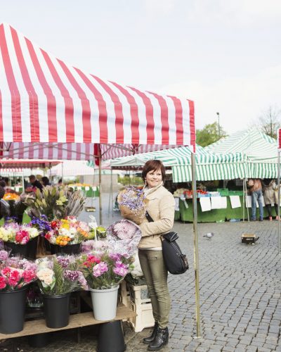 Happy mature woman buying bouquet at flower stall